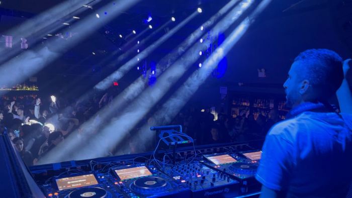 Light beams over the crowd from behind the decks